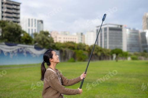 Preview: Woman use 360 degree camera to take video at park