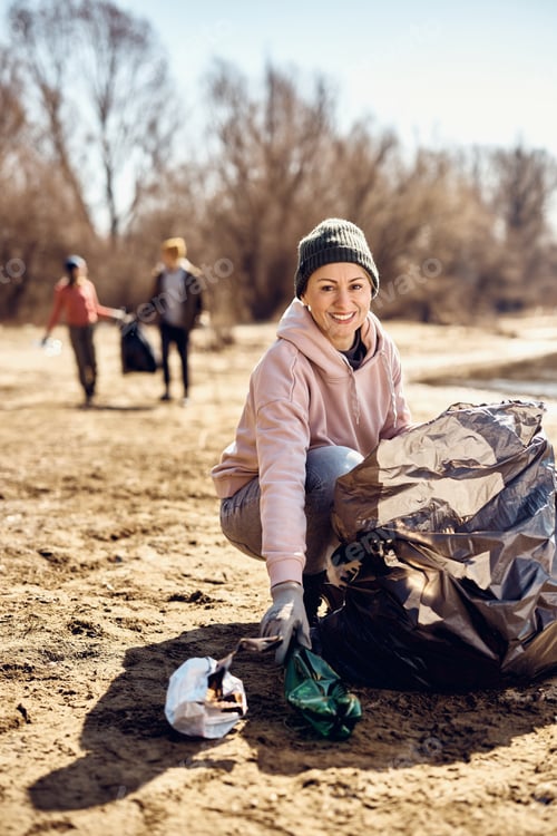 Preview: Happy woman doing community charity work and cleaning beach from the trash.