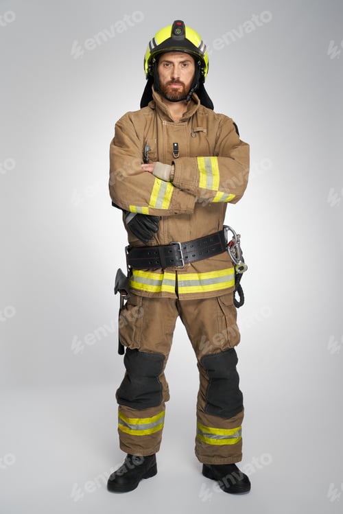 Preview: Serious male firefighter in full gear, posing with crossed hands.