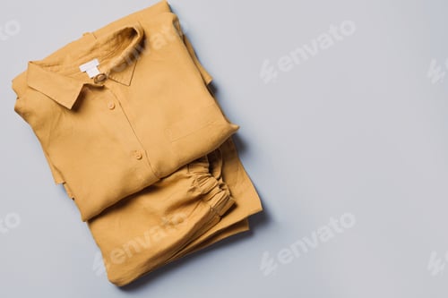 Preview: Folded Yellow Shirt and Pants on Blue Background