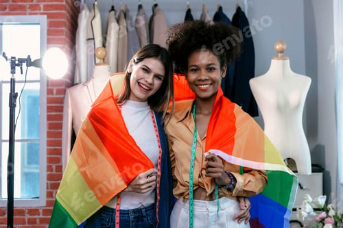 Preview: Happy women standing with a pride rainbow flag.
