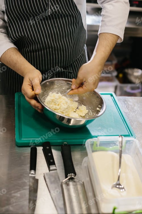 Preview: Close up. A male cook prepares pancake batter in a metal bowl in the kitchen of a restaurant.