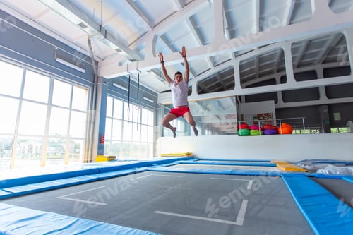 Preview: Fitness, fun, leisure and sport activity concept - Handsome happy man jumping on a trampoline