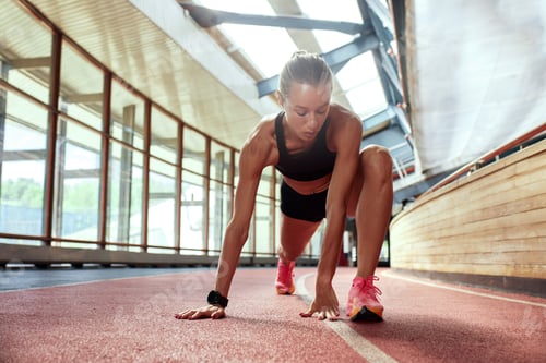 Preview: Young athlete girl is warming up before the race at the stadium. A slender blonde in a black