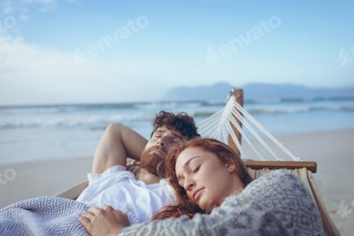 Preview: Front view of relaxed Caucasian couple sleeping on hammock at beach. Ocean in the background