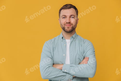 Preview: Cute unshaven man smiling with healthy teeth and crossed arms in mint shirt posing