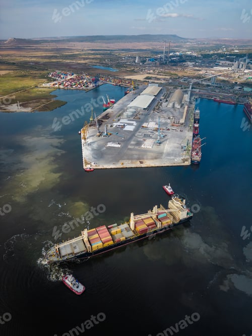 Preview: aerial view of a container ship is seen assisted by two tugboats as it departs the harbor