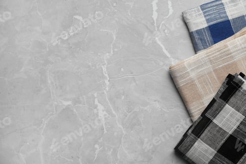 Preview: Folded colorful kitchen towels on grey stone table, top view. Space for text