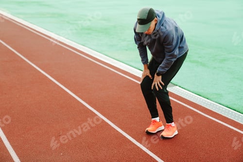 Preview: Young white runner warming up while working out on track