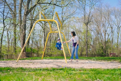 Preview: Mother and diverse toddler girl bonding together as a family on a nice summer day at playground park