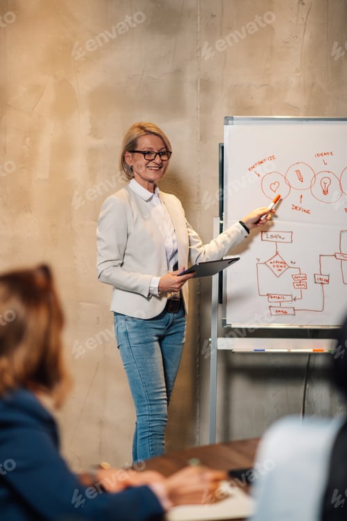 Preview: Senior businesswoman pointing on a whiteboard the statistic during a meeting