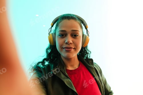 Preview: Young woman wearing headphones taking a selfie while listening to music