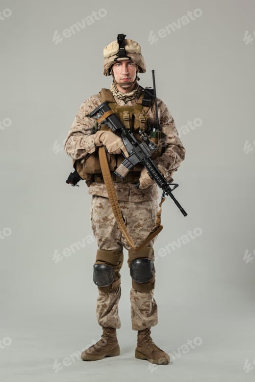 Preview: Soldier stands in uniform with weapon in a studio setting indoors during daylight hours