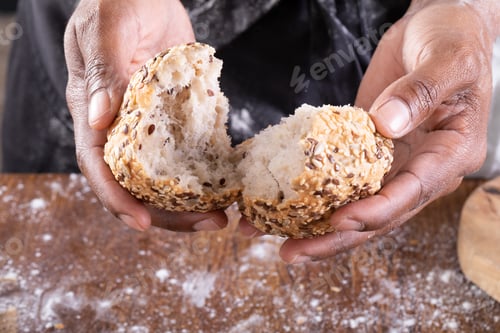 Preview: Close-up of african american male baker breaking bread on table