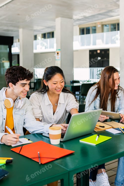 Preview: Happy young group of multiracial students working together on laptop at college