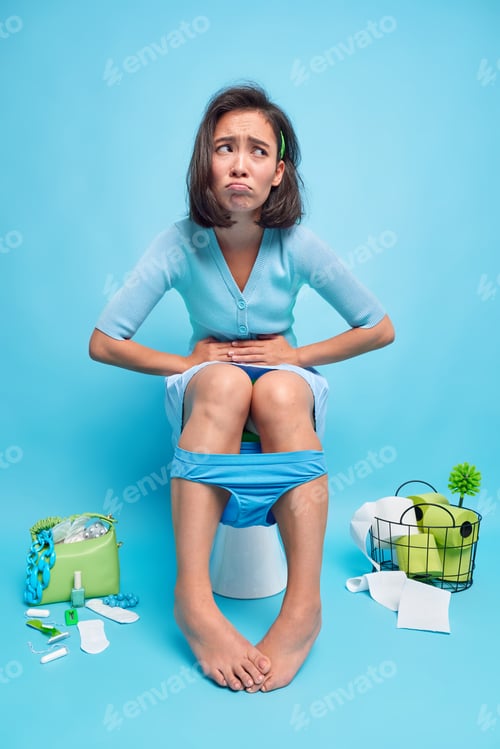 Preview: Indoor shot of displeased Asian woman suffers from stomachache indigestion or diarrhea poses poses t