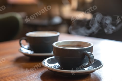 Preview: Closeup image of two blue cups of hot coffee on vintage wooden table in cafe