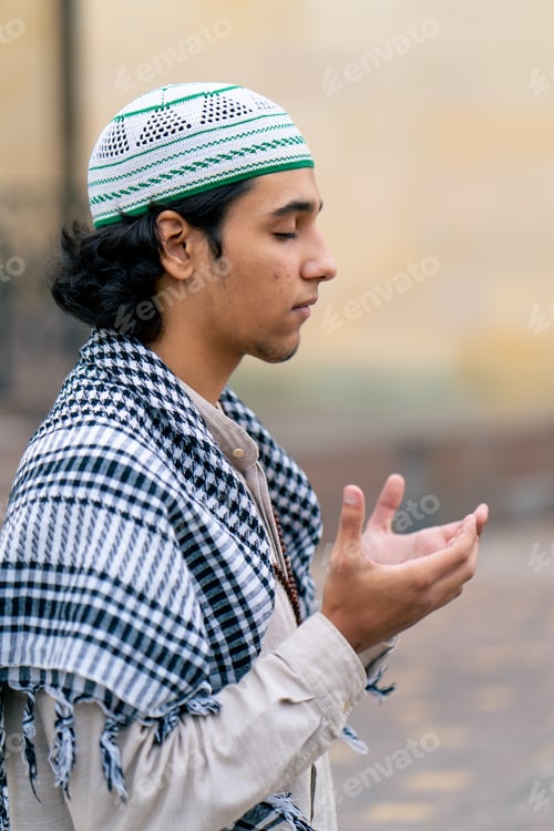 Preview: A guy of Arab appearance in national clothes with a rosary around his neck prays in the courtyard