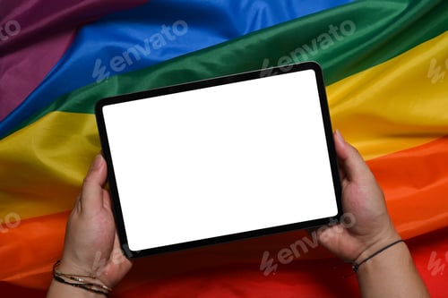 Preview: Man holding digital tablet over LGBT rainbow flag.