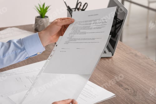 Preview: Businessman putting document into punched pocket at wooden table in office, closeup