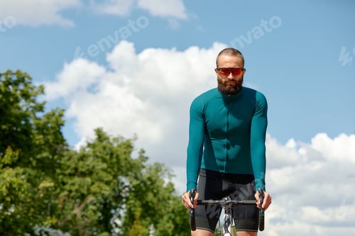 Preview: Portrait of a sporty man in a cycling outfit standing with a bicycle on the Bike Lane, posing for
