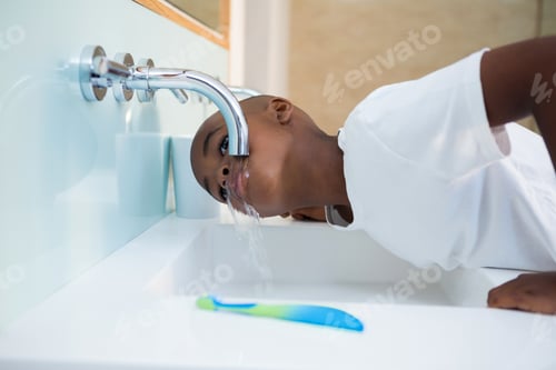 Preview: Side view of boy washing mouth from faucet