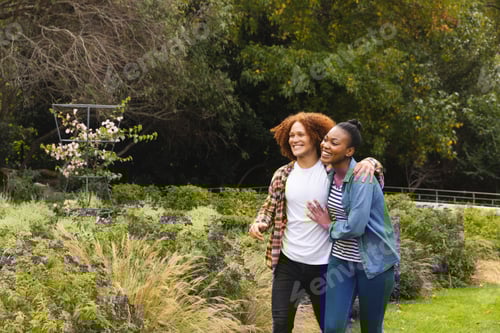 Preview: Happy diverse couple embracing and walking in garden, copy space