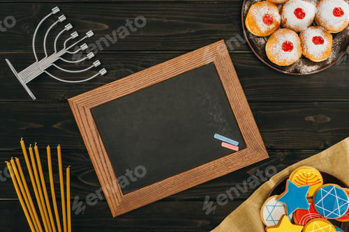 Preview: top view of frame, menorah, donuts and cookies with star of david on wooden tabletop, hanukkah