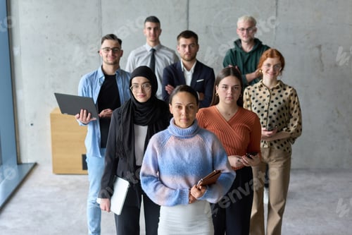 Preview: A diverse and determined team of business professionals stands confidently in an office, ready to
