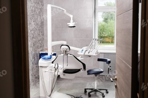 Preview: Through door view at modern dentists office with dental chair