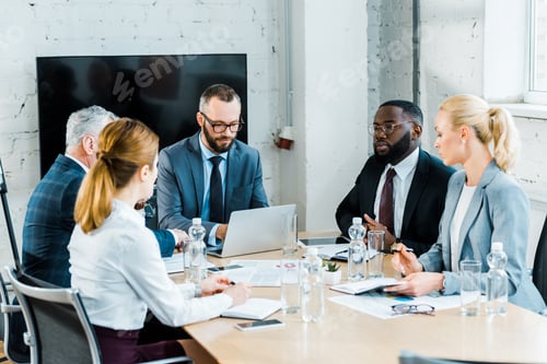 Preview: multicultural businessmen having conversation with businesswomen in conference room