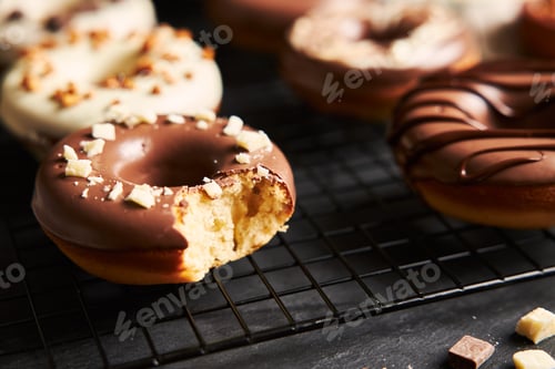 Preview: Beautiful shot of a bitten donut covered in the white and brown chocolate glaze on a black table