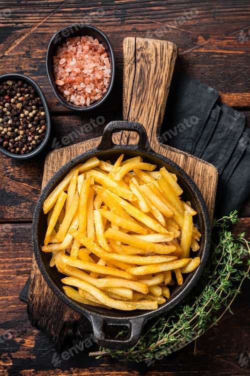 Preview: Skilet full of Potato french fries with salt. Wooden background. Top view