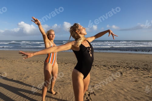 Preview: Two women having fun dancing at sunset on the beach