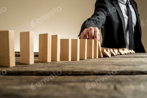 Preview: Businessman stopping domino effect with his finger