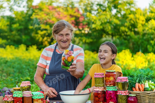 Preview: Women with jar preserved vegetables for the winter mother and daughter. Selective focus.