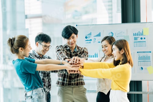 Preview: Happy successful asian business team giving a high fives gesture as they laugh and cheer their