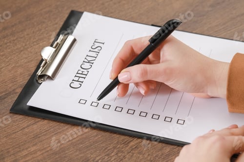 Preview: Woman filling Checklist at wooden table, closeup