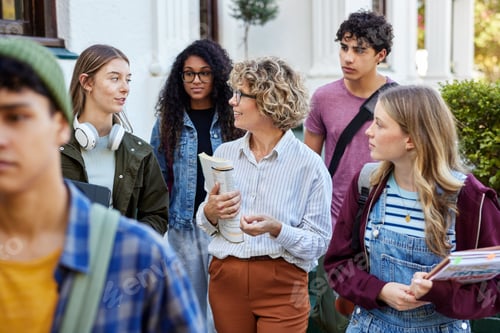 Preview: High school teacher walking with multiethnic students outside school