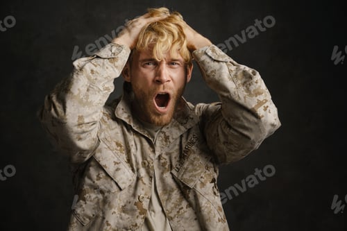 Preview: Unhappy military man with headache holding his head and screaming