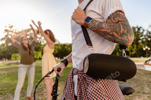 Preview: company of friends having fun together in park listening to music