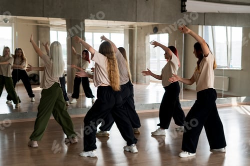 Preview: a team of young female dancers practice choreography in the studio in front of the mirror