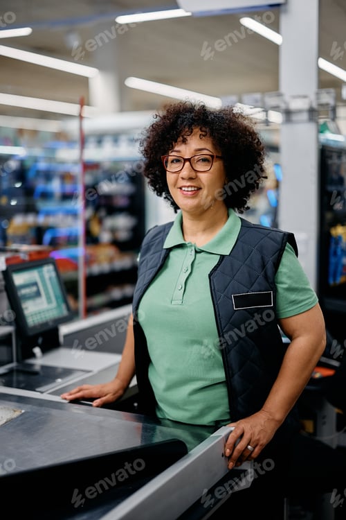 Preview: Happy woman working as supermarket cashier and looking at camera.