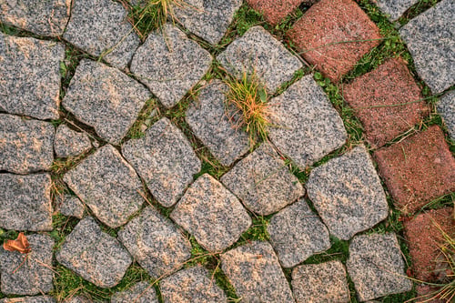 Preview: Background of gray small paving stones with sprouted grass