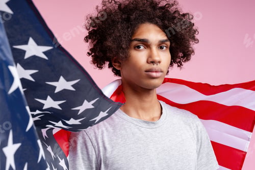 Preview: Young man embracing American flag on pink background