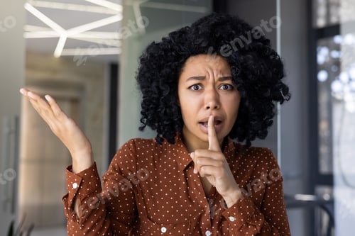 Preview: Woman gesturing for silence in modern office setting