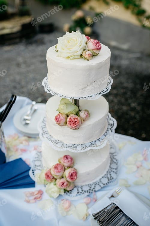 Preview: Delicious three-tiered white and pink wedding cake decorated with delicate pink roses on the top