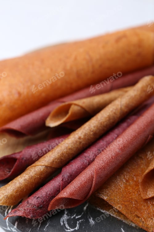 Preview: Delicious fruit leather rolls on table, closeup