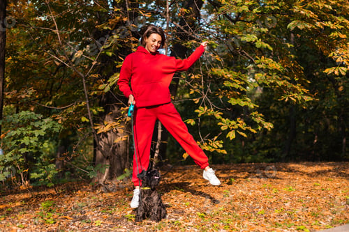 Vista previa: Early morning. Happy woman sleepy eyes with dog in park, autumn orange yellow colors.
