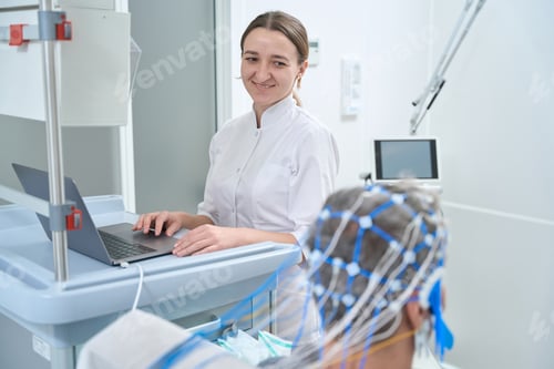 Preview: Friendly female diagnostician performs EEG - electroencephalography in clinic